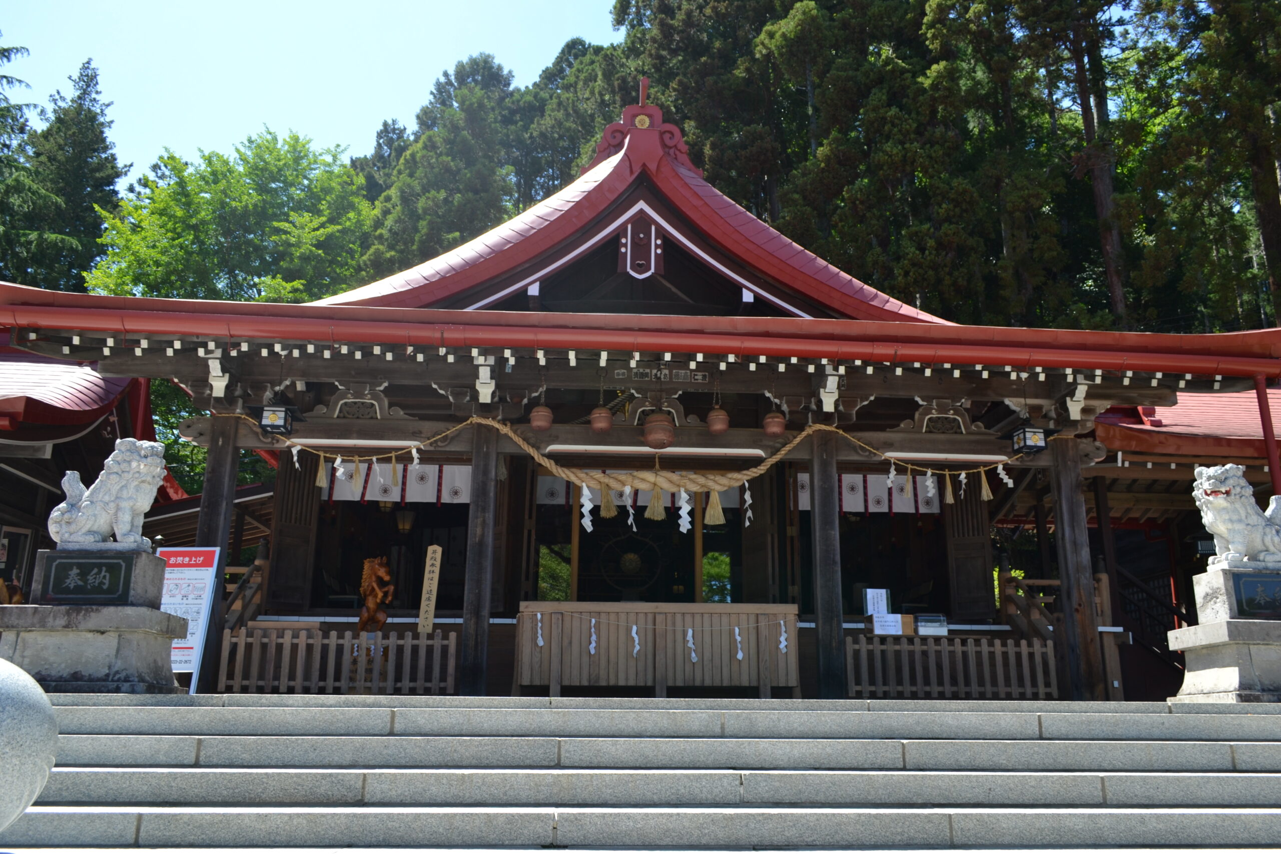金蛇水神社の本殿。赤い屋根と狛犬が印象的な荘厳な社殿